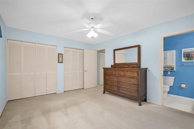 2113 Malcolm Dr, Palm Harbor, FL 34684 - bedroom featuring light colored carpet, multiple closets, connected bathroom, and a ceiling fan