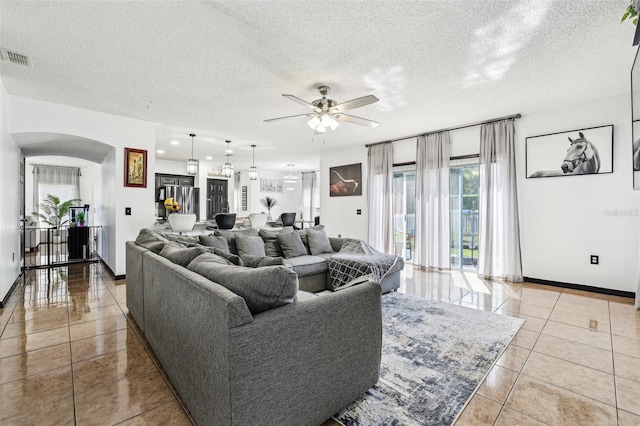 4422 Evergreen Forest Loop, Kissimmee, FL 34758 - living room with arched walkways, tile patterned floors, ceiling fan, baseboards, and a textured ceiling