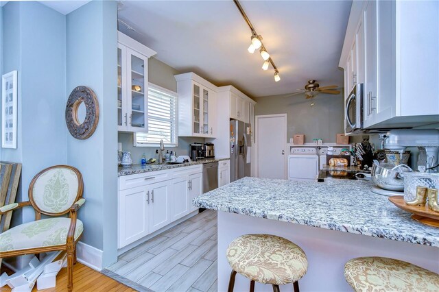 902 W Columbus Dr, Tampa, FL 33602 - kitchen with appliances with stainless steel finishes, a breakfast bar, a sink, glass insert cabinets, and white cabinets