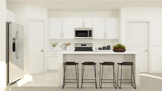 8625 Linked Dr, New Port Richey, FL 34655 - kitchen with appliances with stainless steel finishes, white cabinets, a kitchen breakfast bar, light countertops, and an island with sink