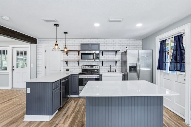 5632 Indiana Ave, New Port Richey, FL 34652 - kitchen featuring appliances with stainless steel finishes, open shelves, a sink, decorative backsplash, and light wood-style floors