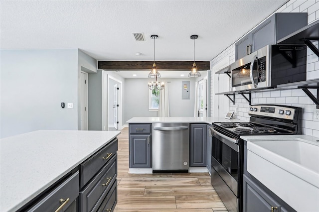 5632 Indiana Ave, New Port Richey, FL 34652 - kitchen featuring stainless steel appliances, light wood finished floors, a peninsula, gray cabinets, and a textured ceiling