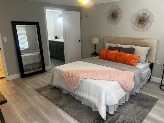 12415 Stagecoach Ln, Hudson, FL 34667 - bedroom with light wood finished floors, baseboards, and ensuite bath