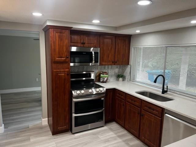 12415 Stagecoach Ln, Hudson, FL 34667 - kitchen featuring appliances with stainless steel finishes, a sink, backsplash, light countertops, and recessed lighting