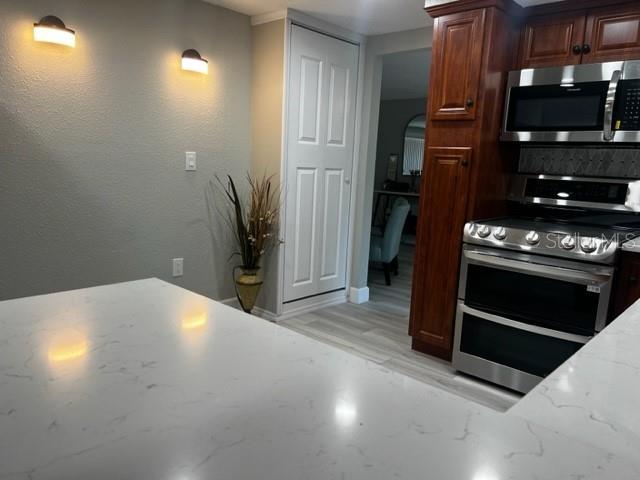 12415 Stagecoach Ln, Hudson, FL 34667 - kitchen featuring appliances with stainless steel finishes, light stone countertops, and arched walkways