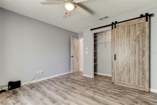 2380 Shelly Dr Unit B, Palm Harbor, FL 34684 - unfurnished bedroom with a barn door, wood finished floors, a closet, baseboards, and a textured ceiling
