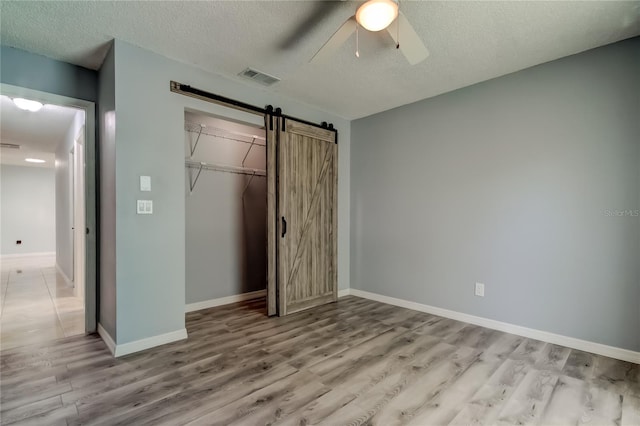 2380 Shelly Dr Unit B, Palm Harbor, FL 34684 - unfurnished bedroom with a barn door, wood finished floors, a closet, baseboards, and a textured ceiling