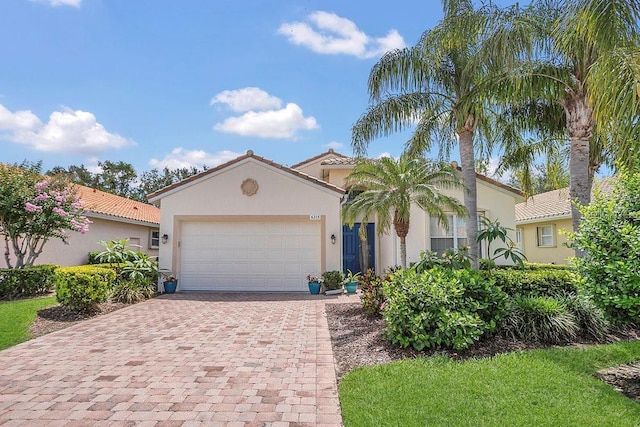 mediterranean / spanish home with decorative driveway, stucco siding, a garage, and a tiled roof