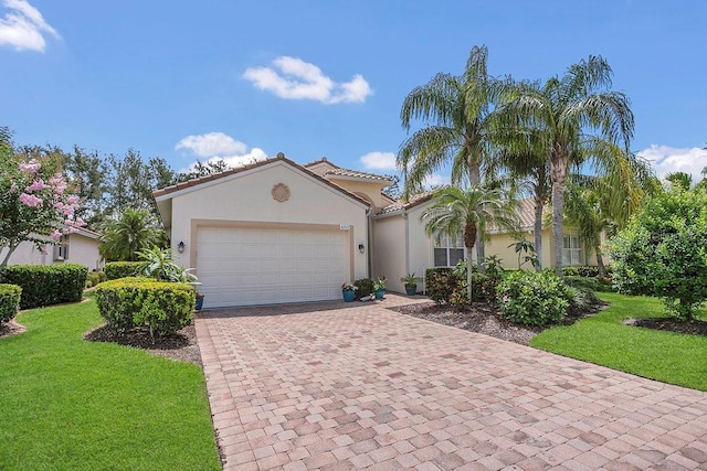 mediterranean / spanish-style house featuring stucco siding, decorative driveway, an attached garage, and a front lawn