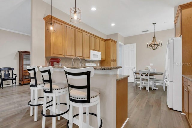 kitchen with white appliances, light wood finished floors, decorative backsplash, a kitchen breakfast bar, and recessed lighting