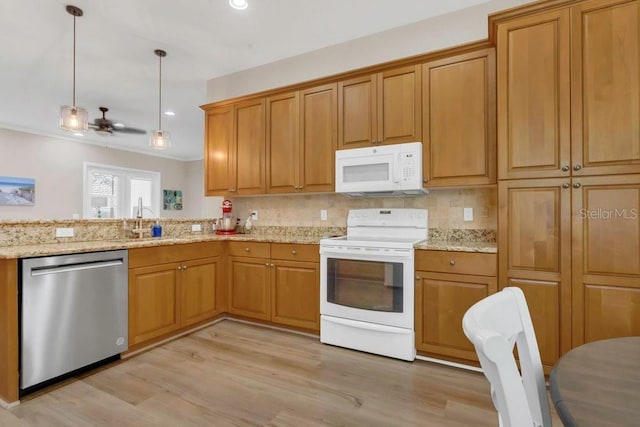 kitchen with white appliances, a sink, light wood-type flooring, brown cabinets, and recessed lighting