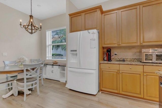 kitchen featuring white fridge with ice dispenser, light wood-style flooring, a chandelier, and hanging light fixtures