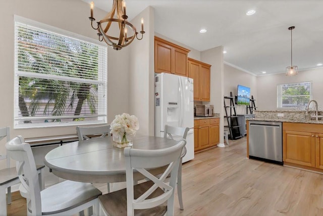 kitchen with stainless steel dishwasher, white refrigerator with ice dispenser, a chandelier, a sink, and crown molding