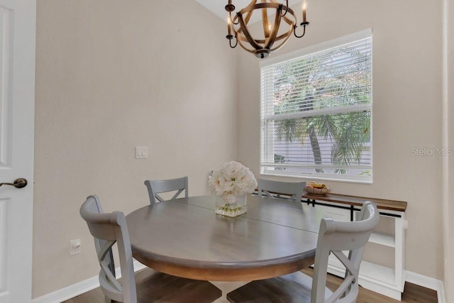 dining area featuring a chandelier, baseboards, and wood finished floors