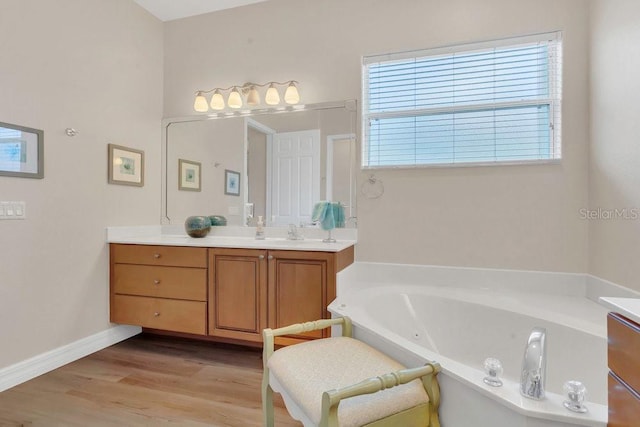 full bath featuring vanity, a garden tub, wood finished floors, and baseboards