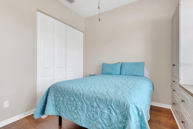 bedroom with wood finished floors, a closet, and baseboards