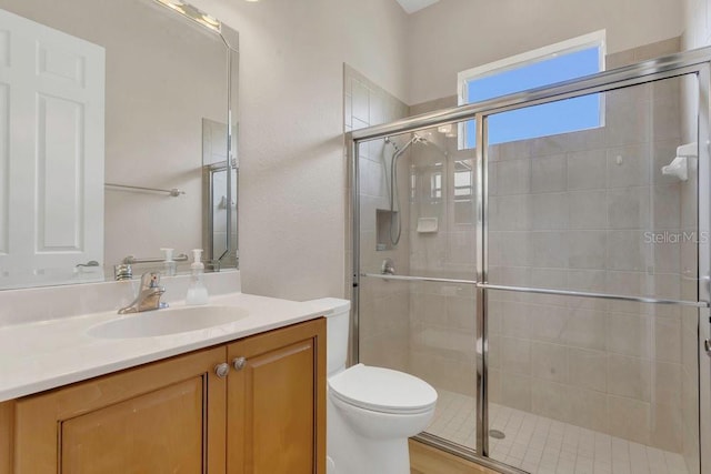 bathroom featuring a stall shower, toilet, and vanity