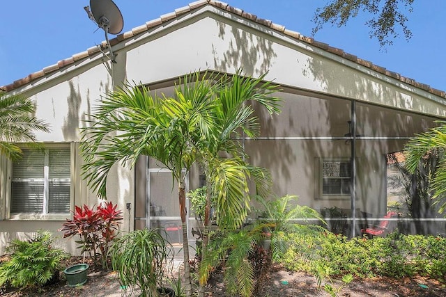 view of home's exterior with stucco siding and a tile roof