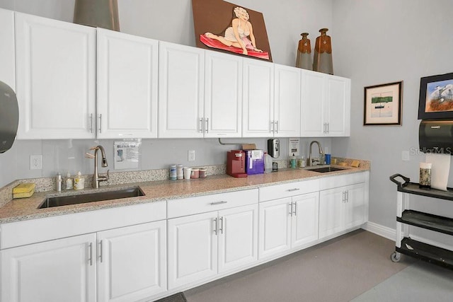 kitchen featuring a sink, white cabinetry, and baseboards