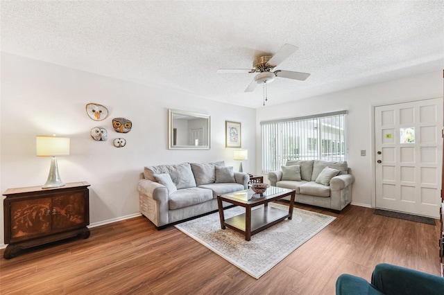 living room featuring a textured ceiling, a ceiling fan, wood finished floors, and baseboards