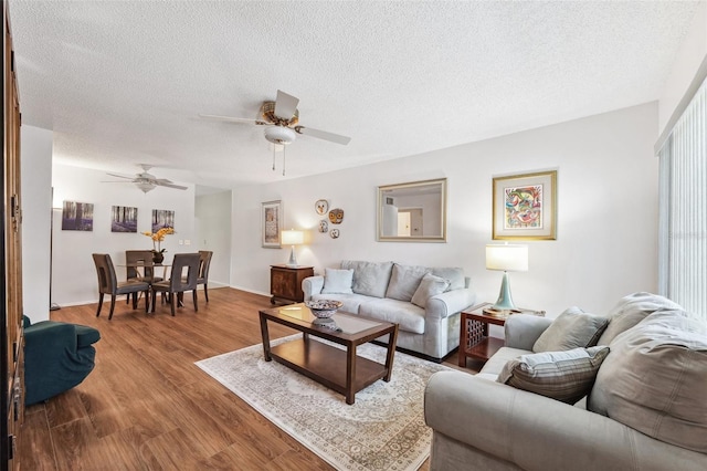 living room featuring ceiling fan, a textured ceiling, and wood finished floors
