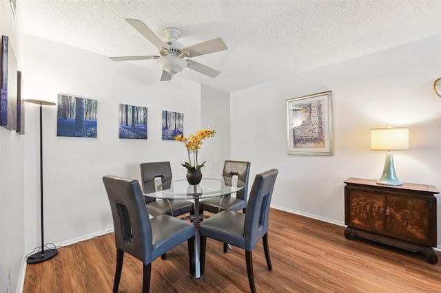 dining room featuring wood finished floors, baseboards, a textured ceiling, and a ceiling fan