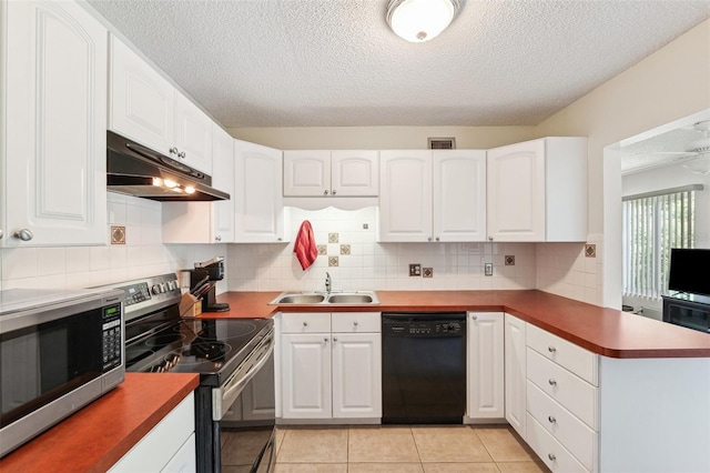 kitchen featuring stainless steel appliances, under cabinet range hood, a sink, a peninsula, and a textured ceiling