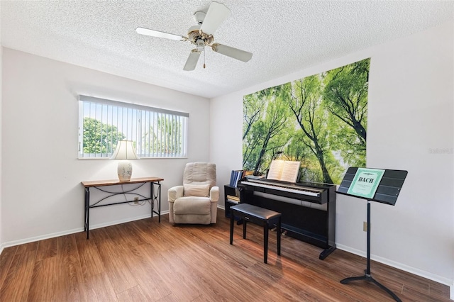 sitting room with a textured ceiling, wood finished floors, a ceiling fan, and baseboards