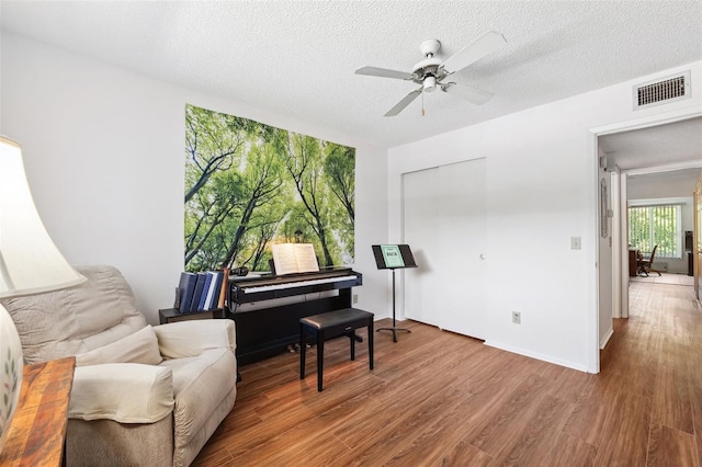 sitting room featuring ceiling fan, wood finished floors, and a textured ceiling