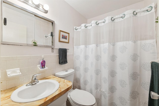 bathroom with toilet, tile walls, a shower with curtain, vanity, and a wainscoted wall