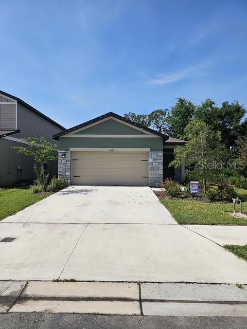10607 Ladybug Cv, Parrish, FL 34219 - view of front of property with an attached garage, stone siding, and concrete driveway
