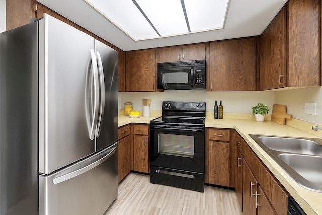 4006 Cypress Ln Unit 4006, Tampa, FL 33618 - kitchen featuring black appliances, a sink, light countertops, and light wood-type flooring