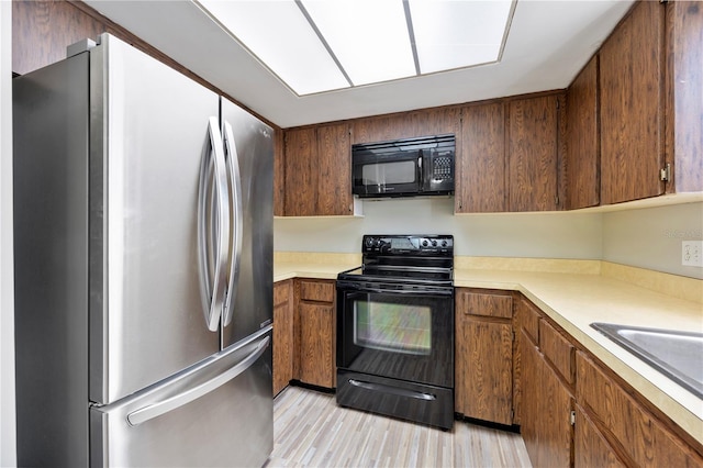 4006 Cypress Ln Unit 4006, Tampa, FL 33618 - kitchen featuring black appliances, light countertops, a sink, light wood-style flooring, and brown cabinets
