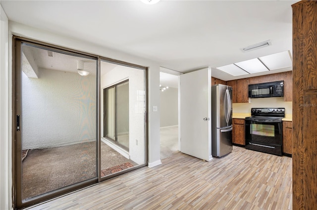 4006 Cypress Ln Unit 4006, Tampa, FL 33618 - kitchen with black appliances, light wood-style flooring, light countertops, and brown cabinetry