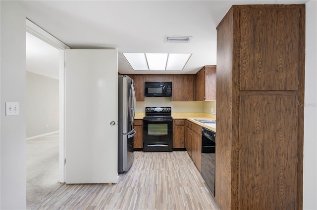 4006 Cypress Ln Unit 4006, Tampa, FL 33618 - kitchen with black appliances, light countertops, light wood finished floors, and a sink