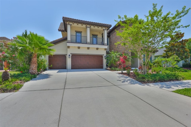 mediterranean / spanish house with a balcony, driveway, stucco siding, and an attached garage