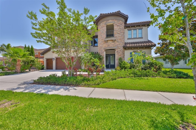 mediterranean / spanish home with a tile roof, concrete driveway, stucco siding, a front yard, and stone siding