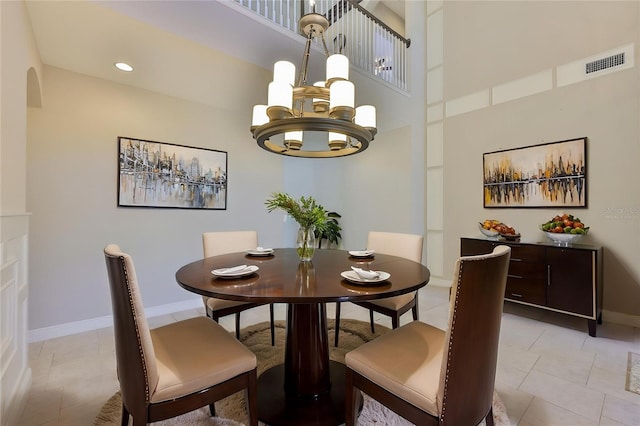 dining room featuring a chandelier, baseboards, light tile patterned floors, and a high ceiling