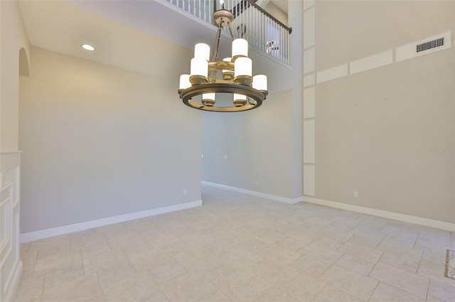 spare room with a chandelier, a high ceiling, baseboards, arched walkways, and recessed lighting