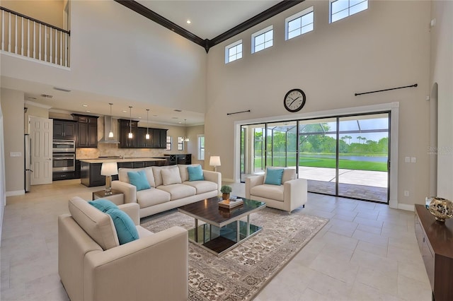 living room with ornamental molding, a towering ceiling, and baseboards