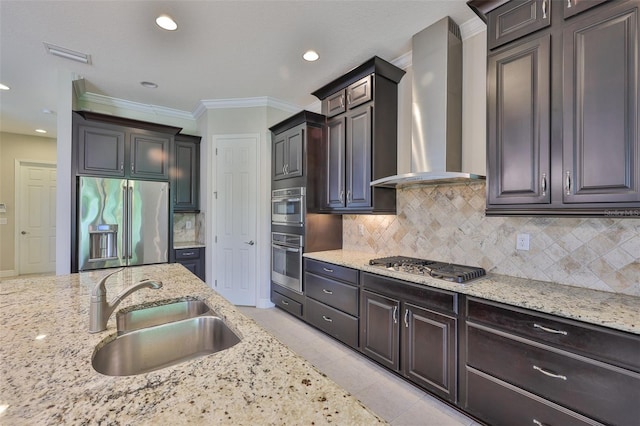 kitchen with wall chimney exhaust hood, a sink, appliances with stainless steel finishes, light stone countertops, and crown molding