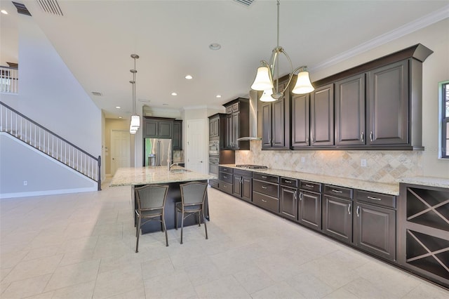 kitchen featuring appliances with stainless steel finishes, wall chimney exhaust hood, backsplash, light stone counters, and ornamental molding
