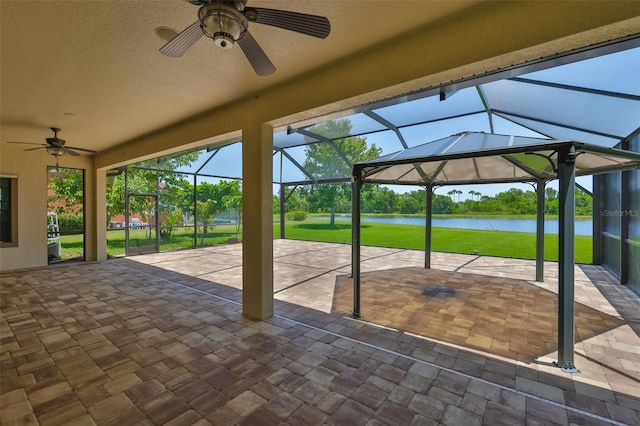 view of patio / terrace featuring ceiling fan, a water view, and glass enclosure