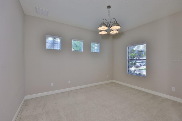 spare room with a chandelier, light carpet, and baseboards