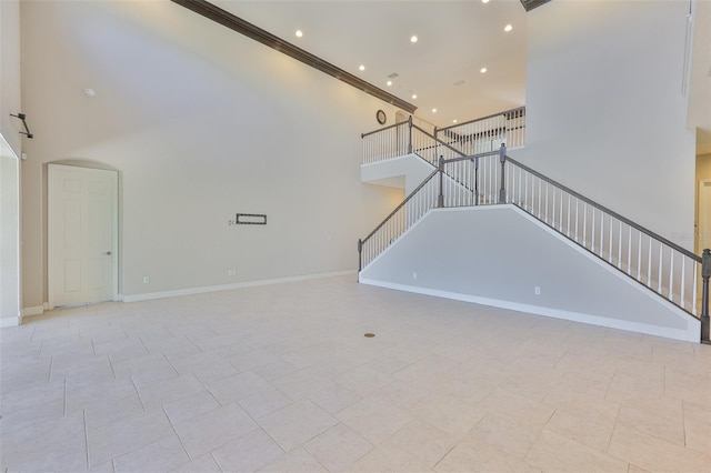 unfurnished living room featuring stairs, a high ceiling, recessed lighting, ornamental molding, and baseboards