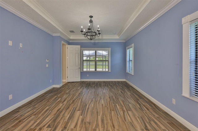 spare room featuring a chandelier, wood finished floors, baseboards, and ornamental molding