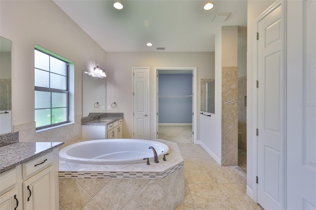 bathroom featuring a garden tub, walk in shower, vanity, a spacious closet, and recessed lighting