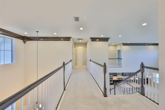 hallway with an upstairs landing, recessed lighting, carpet floors, and arched walkways