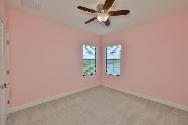 empty room with light colored carpet, baseboards, and a ceiling fan