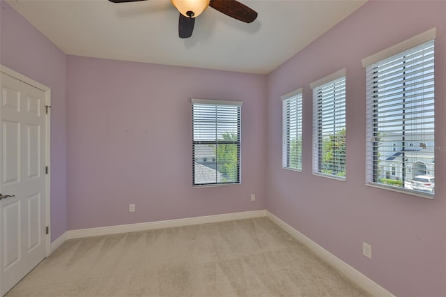 empty room featuring ceiling fan, light carpet, and baseboards
